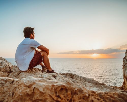Lonely guy observing the sunset from a cliff in Cyprus